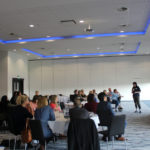 An event with a room full of guests listening to a speaker present