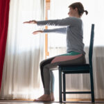 Woman at home doing exercise sat on a chair