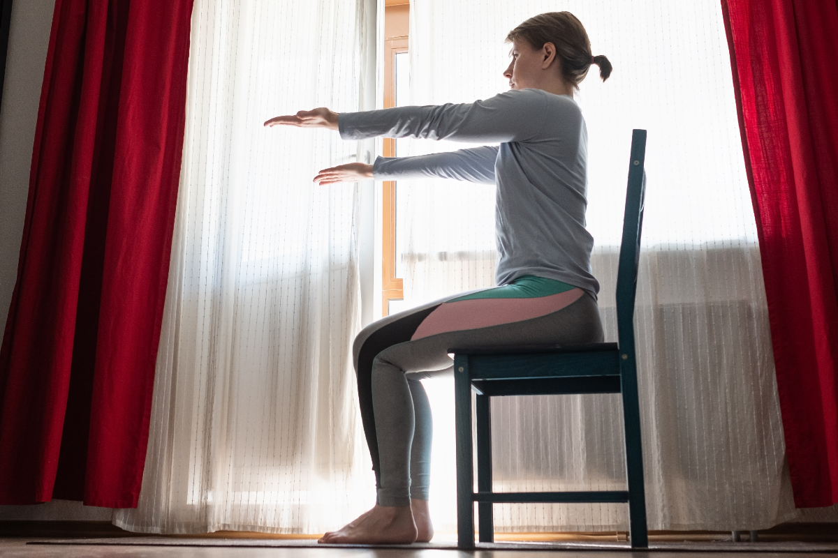 Woman at home doing exercise sat on a chair