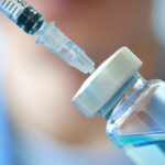Close up doctor's hand holds a syringe and treatment bottle