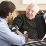 Elderly man has blood pressure checked by doctor