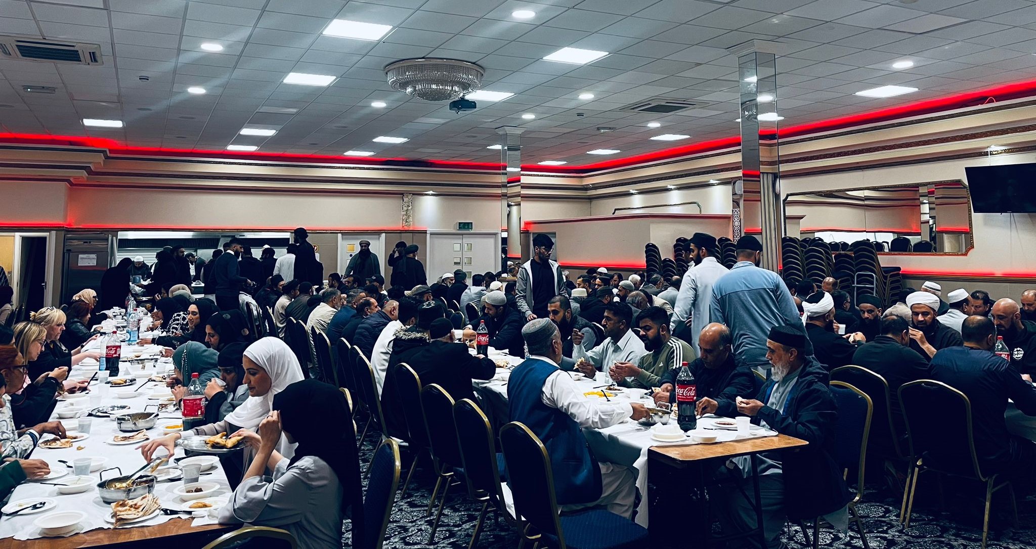 Members of the community seated at tables eating food.