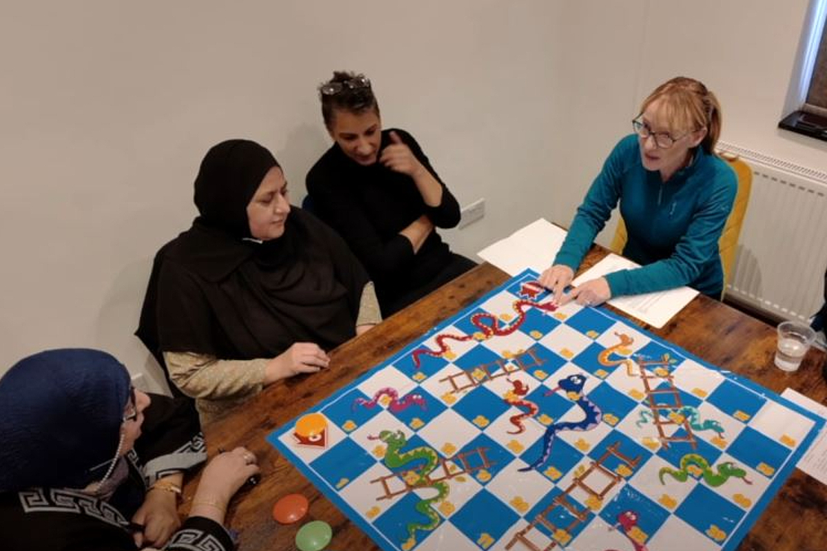 Members of the South Asian community in Rochdale discussing the Greater Manchestedr healthcare system, with the aid of a snakes and ladders board.